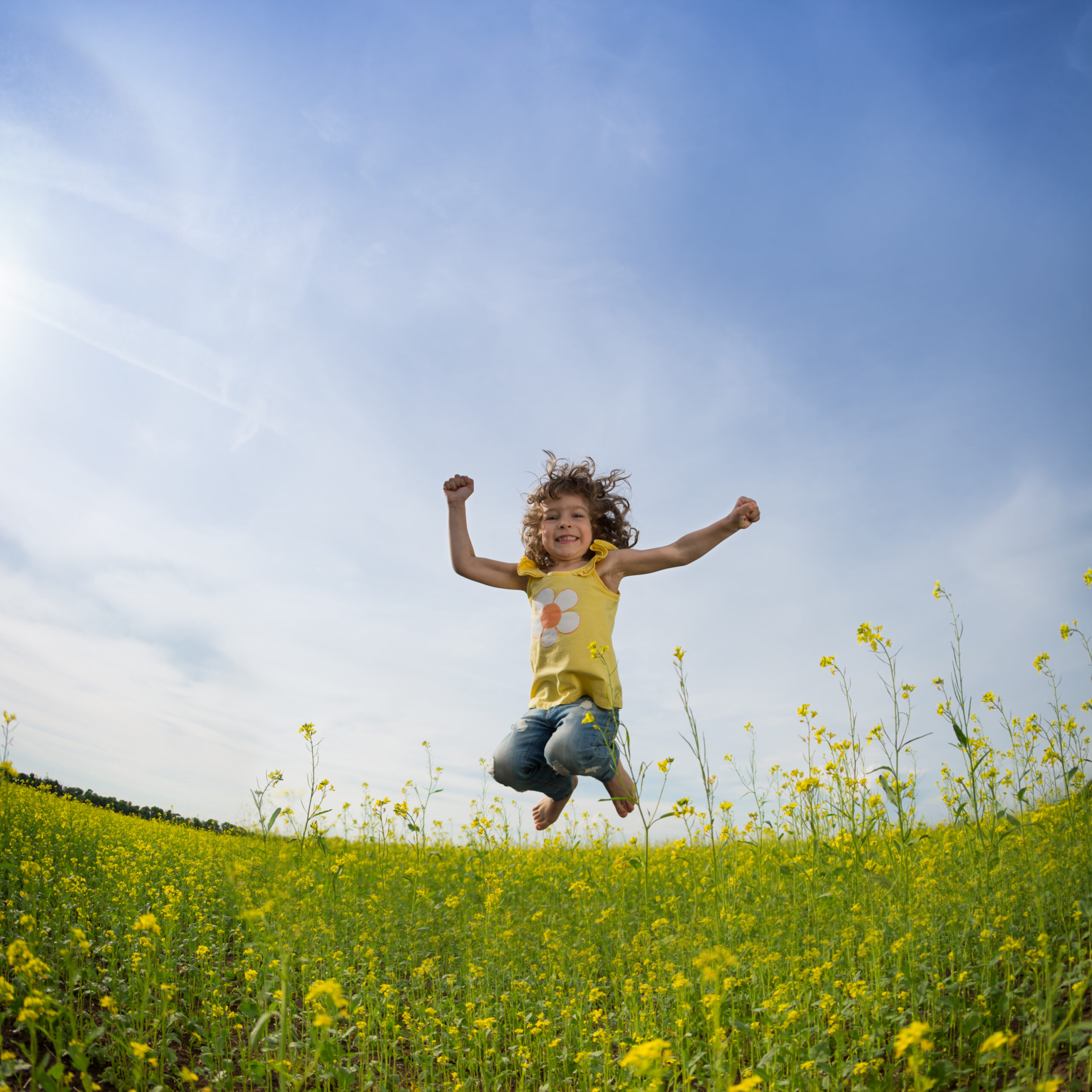Child jumping for joy in a field of yellow wildflowers